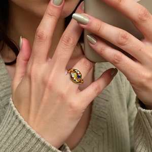 Detail of a gold double-layered curved ring set with clear, red, and blue gemstones