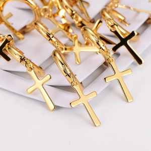Detailed macro view of multiple gold cross pendant earrings displayed on a white card