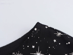 Macro del tessuto a rete nera con motivi di stelle argentate lucide e trama delicata