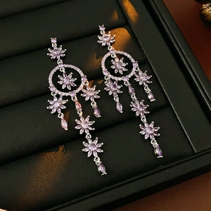 Macro shot of silver dreamcatcher earrings with purple crystals on black leather