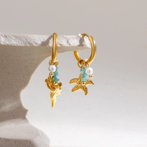 Créoles dorées avec étoile de mer, conque, perles et perles bleues sur socle en pierre