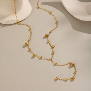 Detail of gold Y-shaped necklace featuring polished beads on a delicate chain link
