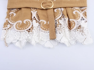 Detail of khaki blouse featuring white lace embroidery and belt with gold metal ring buckle