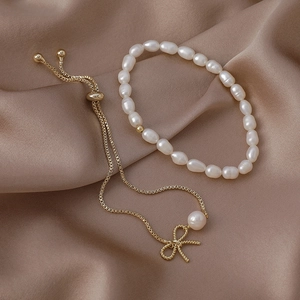 Macro detail of French Baroque freshwater pearl bracelet with a golden bow on silk