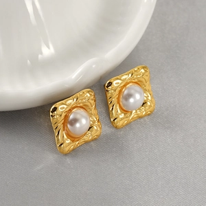 Macro detail of vintage gold square earrings with hammer texture and white pearl inlay