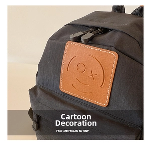 Detail shot of black canvas backpack with a cartoon leather smiley patch and double zippers