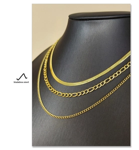Three-layer gold stainless steel necklace set with figaro and snake chains on a black bust