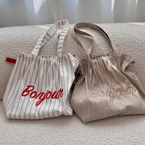 Detailed view of striped canvas tote bags with Bonjour embroidery and drawstring closure