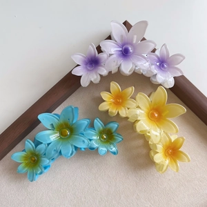 Close-up of candy-colored floral hair claws in gradient blue, yellow, and purple hues