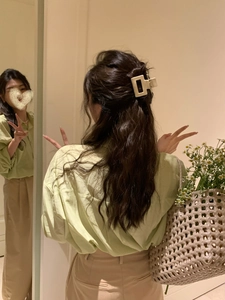 Detail showing a beige rectangular matte acetate hair claw clip styled on the hair