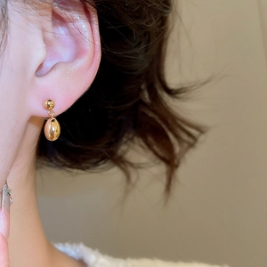Gros plan sur des boucles d'oreilles goutte en or 18 carats portées par un mannequin