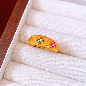 Macro detail of vintage gold flower ring with colorful gemstones and textured finish