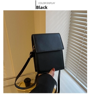 Detail of minimalist black faux leather shoulder bag with fine stitching and flap closure