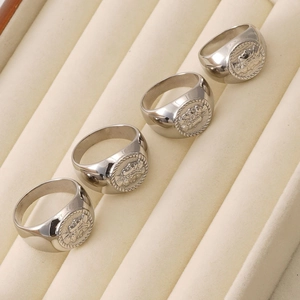 Set of four silver stainless steel signet rings with embossed relief badge designs