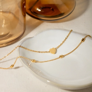 Detail of 18K gold double layer necklace with heart pendant and delicate bead chain