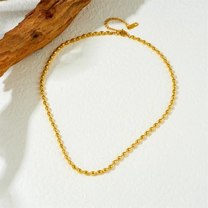 Elegant gold plated stainless steel football bead chain necklace on white textured background