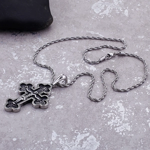 Retro silver steel cross necklace with religious carving and twisted chain on grey background