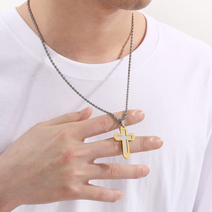 Gros plan d'un pendentif croix or et argent sur une chaîne torsadée porté par un homme