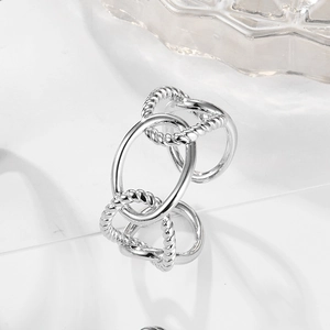 Macro detail of intertwined S925 sterling silver bands with twisted rope texture and high polish