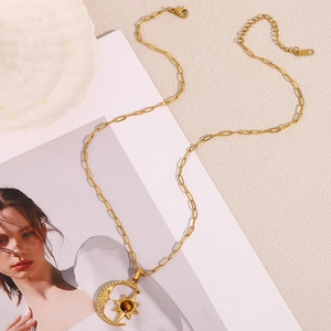 Detail of 18K gold-plated star and moon pendant necklace with crystal and brown gemstone