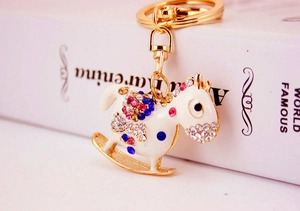 Detailed close-up of a rocking horse keychain with rhinestones and white enamel finish