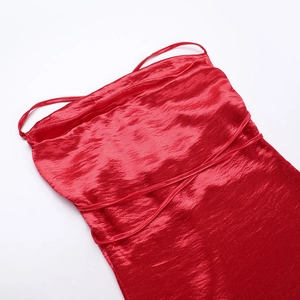 Detail of red satin dress featuring elegant pleats and delicate spaghetti straps