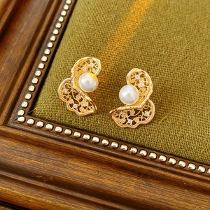 Detail van gouden holle bloemblaadjes oorbellen met parel en fonkelende zirkonia-accenten
