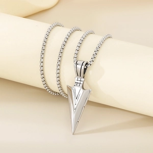 Detailed close-up of a silver arrow pendant with geometric textures and box chain