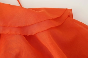Macro detail of vibrant orange sheer fabric with layered ruffles and delicate rolled edges
