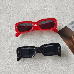 Flat lay of vintage rectangular sunglasses in red and black frames on a textured background
