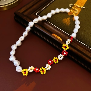 Detail of beaded flower necklace with white pearls and colorful seed beads on wood