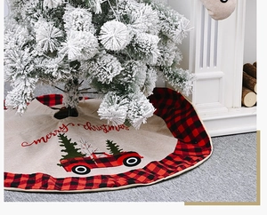 Linen Christmas tree skirt with red truck motif under a snowy tree by a fireplace