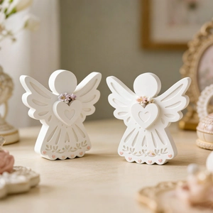 Detail showing two white angel resin figurines with heart patterns and lace textures