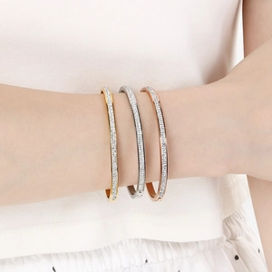 Detailed view of stacked gold, silver, and rose gold crystal bangles on a wrist