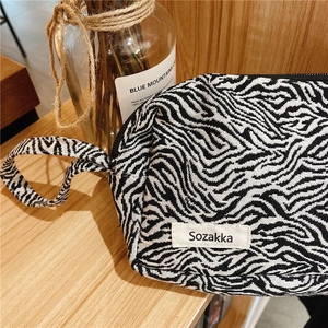 Détail de la pochette en toile zébrée noir et blanc avec poignée et étiquette tissée