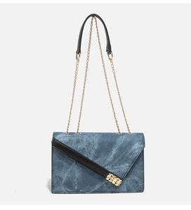 Detailed macro view of denim blue crossbody bag with gold chain strap and metal lock buckle
