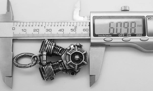 Macro view of silver engine pendant on digital caliper measuring 60.98 mm in length