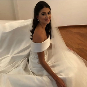 Elegant white satin off-shoulder wedding dress with long veil and waist belt