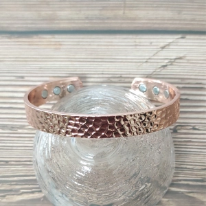 Magnetische koperen armband in roségoud met golfpatroon en magneten op standaard