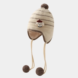 Detail of beige striped knit hat showing plush pom-poms and cute puppy patch for kids