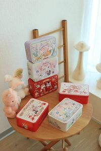 Assorted colorful Christmas tin boxes with festive illustrations on a rustic wooden table