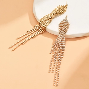 Detail of long gold tassel earrings featuring sparkling white rhinestones on a stone tray