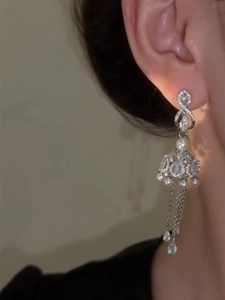 Detail of elegant silver tassel drop earrings with pearls on model side profile