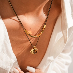Close-up of double-layered 18k gold plated necklace with tiger eye stone pendant