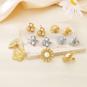 Macro shot of elegant floral pearl earrings on a beige stone base with gold accents