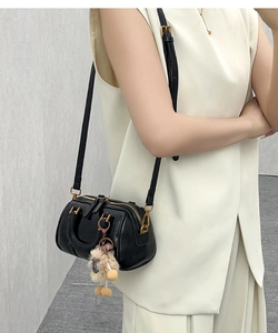Classic black Boston bag with gold hardware and plush charm shown on a model