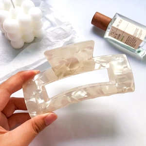 Detail of a large cream acetate hair claw clip with marble texture for elegant styling
