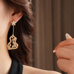 Gros plan de boucles d'oreilles fleur et gourde dorées avec zircons sur un mannequin
