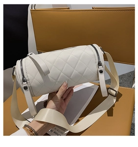 Close-up of quilted white cylinder bag with silver dual zippers and wide fabric strap