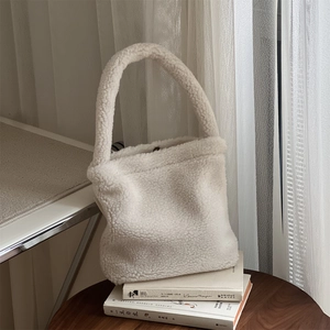Close-up of fluffy white faux fur tote bag on books with soft natural lighting
